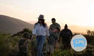 2 Children and 2 adults walking through the bush with the guide following