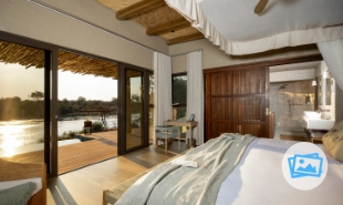Bed looking through large window at the deck and the veld beyond